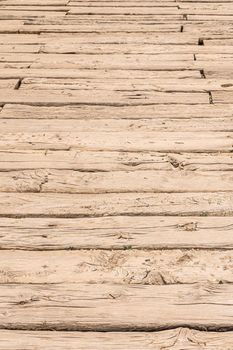 From above full frame of sun dried wooden planks with cracks on uneven surface in daylight