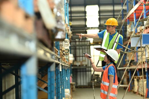 Storehouse employees using barcode scanner to scanning box and checking inventory in a large warehouse.