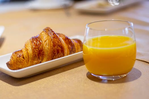 breakfast of a delicious baked croissant and freshly squeezed orange juice. soft focus