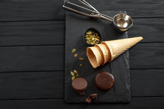 The process of making ice cream in a waffle cup. Top view. Ingredients for the ice cream on the dark wooden background.