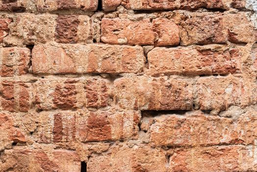 Textured background of rough surface of shabby brick stone wall of old building in daylight