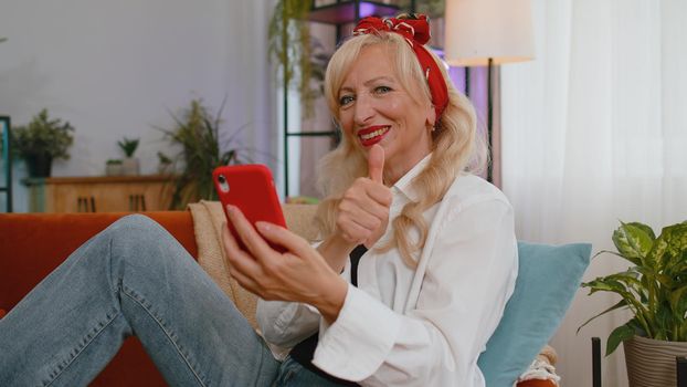 Senior old grandmother woman using smartphone typing new post on web, browsing, searching, addiction of social networks, show thumbs up like, positive feedback, recommends wifi cellular connection 5G