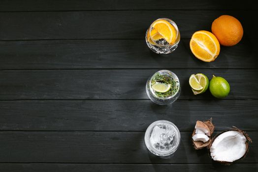 Set of different hard seltzer cocktails on a black wooden background. Top view. Cocktail with lime orange and coconut. Three cold drinks. Copy space