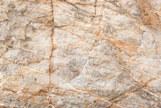 Textured backdrop of rough rocky gray uneven surface with cracks and scratches in daylight