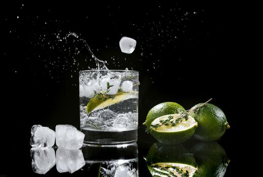 hard seltzer with lime on a dark wooden background, ice cubes fall into a glass with an alcoholic beverage hard seltzer splashes of drink