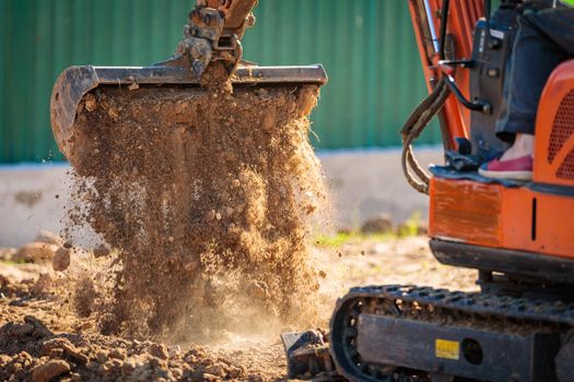 A minitractor rakes the earth with a bucket. Land works