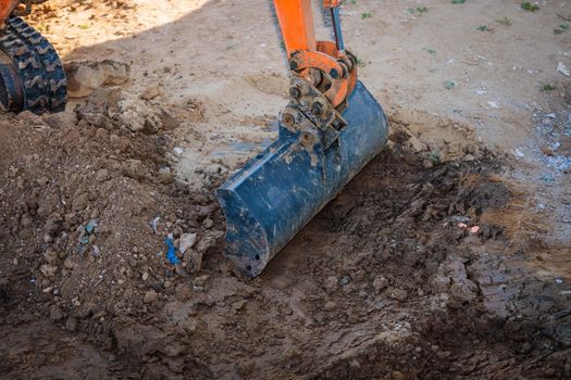 A minitractor rakes the earth with a bucket. Land works