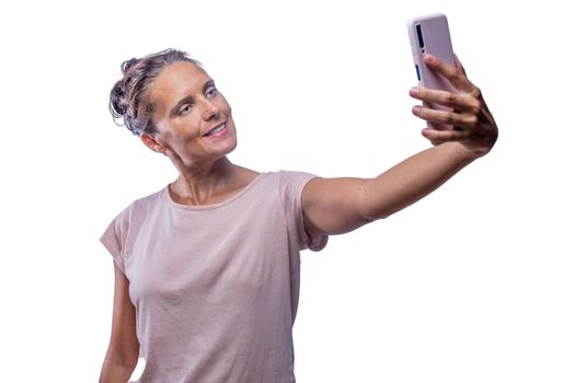 Front view of a green-eyed woman taking a selfie with her mobile phone on a white background.