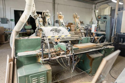 Interior of carpentry factory equipped with dusty automatic wood turning machine producing timber planks