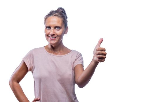 Front view of a green-eyed woman smiling and showing thumb up on a white background with copy space.