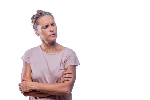 Front view of a distrustful woman with crossed arms on a white background looking to a side with copy space.