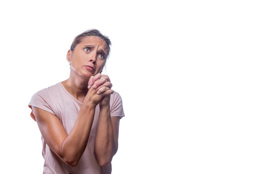 Front view of a green-eyed woman begging and praying with hands together with hope expression on face on a white background with copy space.