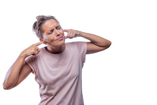 Front view of a woman who covers her ears due to excessive noise on a white background with copy space.