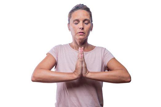 Front view of a woman standing meditating in prayer pose on a white background.