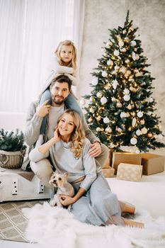 Happy family: mom, dad and pet. Family in a bright New Year's interior with a Christmas tree.