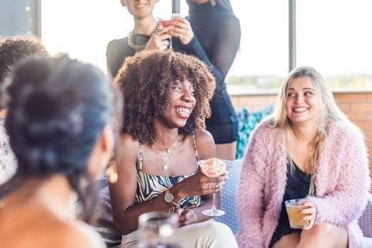 An African American woman sitting on a terrace with her friends drinking and having a good time.