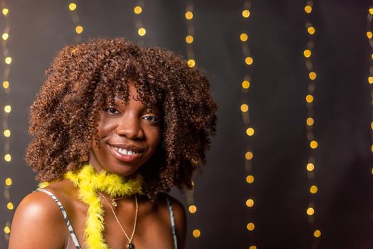 A smiling African American young woman with curly hair looking at camera on a blurred light background.