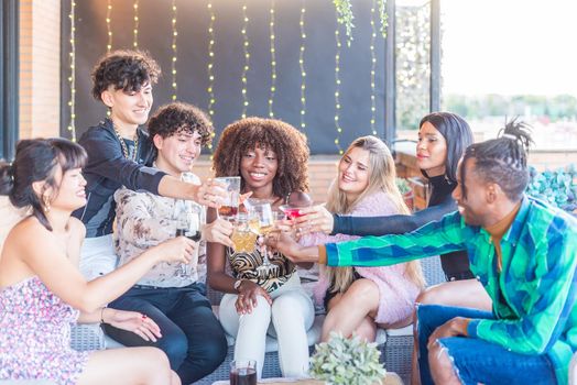 Friends celebrating and toasting with drinks on a terrace during the day.