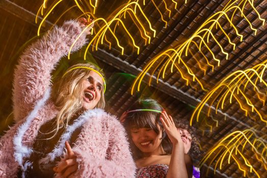 Low angle view of young women having fun with hands up with their friends in a party