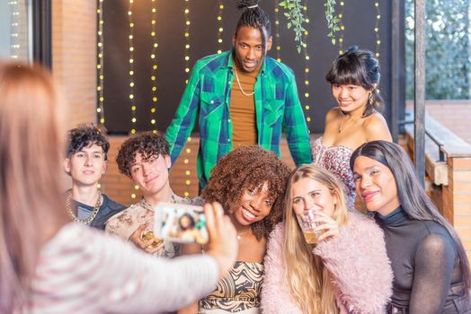 An unrecognizable woman taking a photo with a smartphone to a group of multi-ethnic friends in a terrace