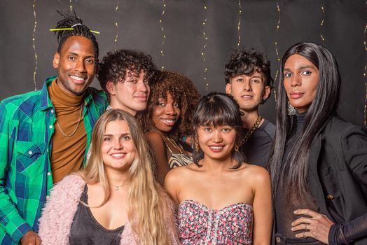 Portrait of a group of multi-ethnic friends posing and looking at camera on a blurred lights background.