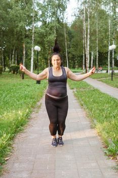 A charming brunette woman plus-size body positive practices sports in nature.