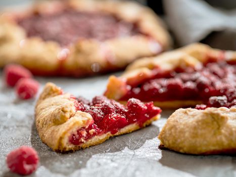 Slice of perfect raspberry galette. Delicious rustic homemade tart with frozen or fresh raspberries on gray background. Beautiful piece of galette with raspberries, copy space
