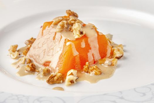 Traditional pumpkin dessert with tahini and walnuts on a white porcelain plate