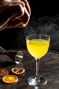 Professional female bartender flavoring a luxury cocktail with impressively spray from citrus peel. Cocktail zest shoot