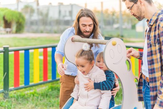 Front view of a little boy playing slider holding little sister at playground.