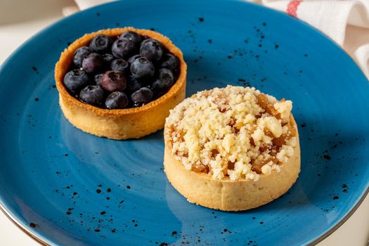 Freshly baked single portion blueberry and apple pie on a blue porcelain plate