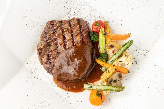 Grilled beef tenderloin with grilled vegetables on a white porcelain plate