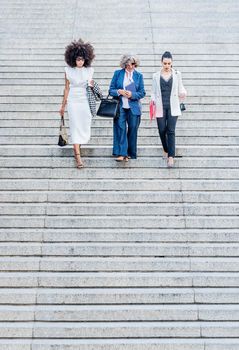 three female co-workers returning from work together. Descending stairs