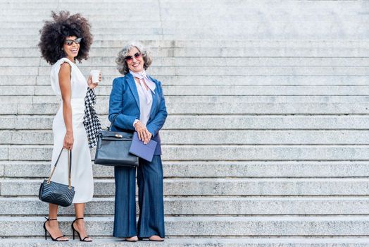 two corporate women smiling and posing well-dressed, horizontal portrait