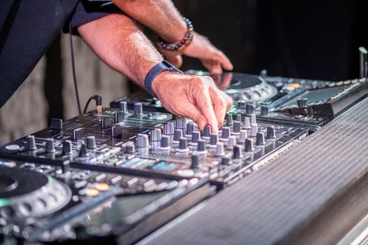 Dj playing disco house progressive electro music at the concert. DJ hands on equipment