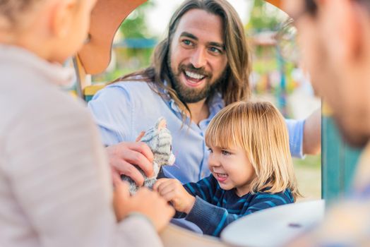 Portrait of a little boy playing with a stuffed cat with his little sister and two dads at the playground.