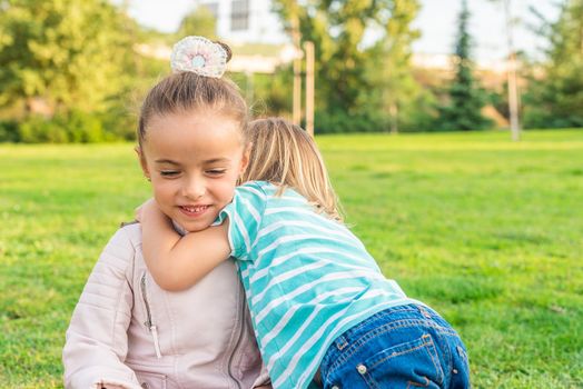 Front view of a little boy hugging his little sister in the park.