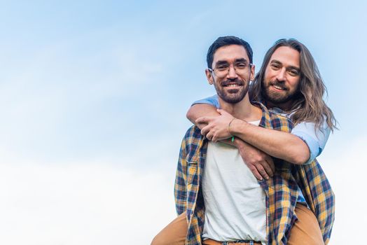 Front view of a young man carrying his partner on his back looking both at camera with copy space