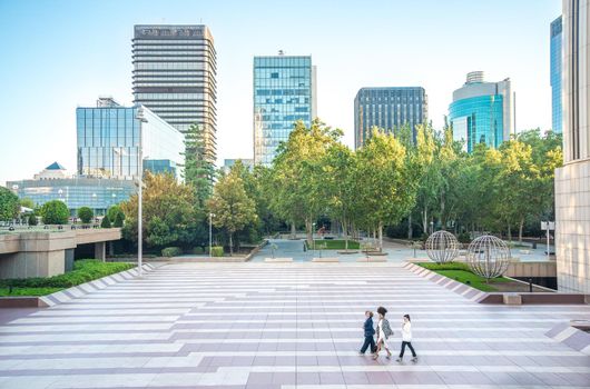 general view of three women walking with park and skyscrapers in background, horizontal