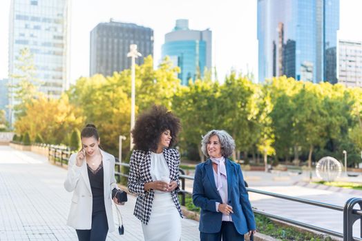 Team of business women walking through the city, horizontal blurred background