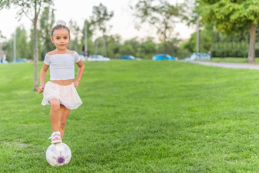 Front view of a little girl posing with soccer ball at park-