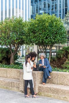 three co-workers resting together surrounded by skyscrapers, vertical picture