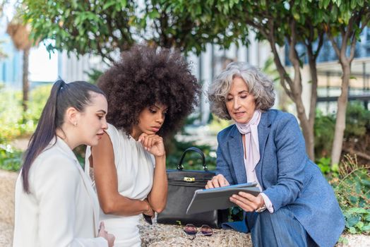 boss showing her work to two female employees outside the office, horizontal close up