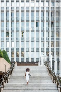 Business woman with afro hair going down the stairs