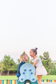 Vertical image of a little brother and sister playing and screaming on a geme of the playground with copy space