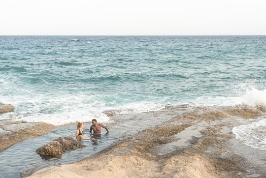 two young people bathing in the sea, view from a distance, horizontal