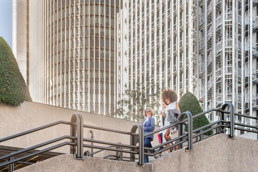 side view of businesswomen on their way home from work. Horizontal view with skyscrapers in the background