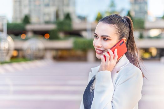 Female person smiling while talking on the phone. Portrait with defocus background