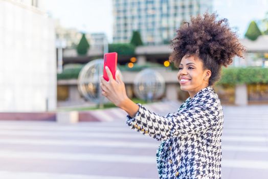 black woman taking a selfie smiling with a red mobile phone, horizontal blurred background