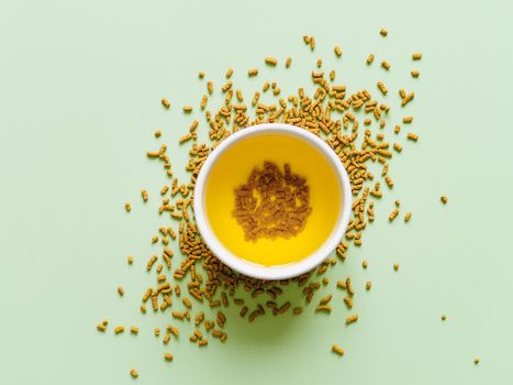 cup of buckwheat tea on light green background. Top view of healthy soba tea or kuqiaocha over groats on green background. Flat lay. Copy space.